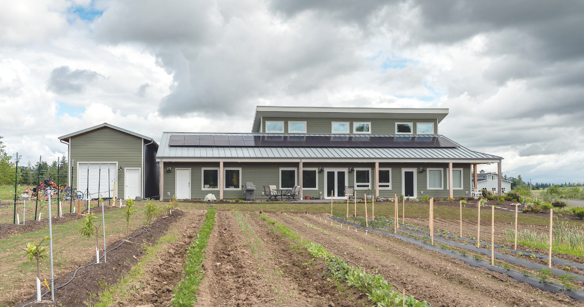 TC Legend Everson Net-Positive home exterior with solar panels, native planting, and vegetable gardens, photo credit Zigzag Mountain Art